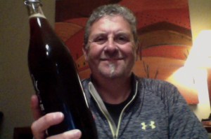 Man with lots of hair waves a beer 